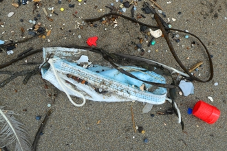 A discarded face mask amongst other plastic pollution found on a Cornish beach