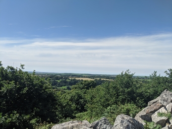 an impressive view of patchwork fields, blue skies and the ocean beyond from a vantage point at Bolts Quarry Farm, identifiable by the impressive rock pile in the foreground