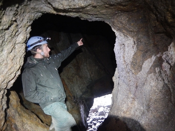 A man stands in a cave and points 
