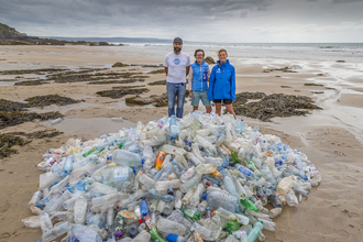 Bottle mountain on Cornish beach with ReFILL Cornwall team behind, photo by Symages