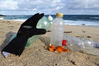 Wetsuit glove and plastic bottles on a Cornish beach