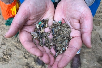 Two hands holding microplastics