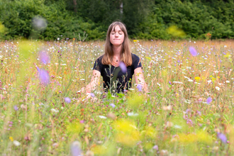 A young women meditates in a beautiful wildflower meadow