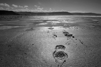 Beautiful black and white seascape with footprints in the sane