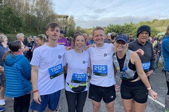 A group of four runners standing in a line, smiling at the camera.