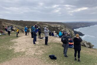 A group of people watch for wildlife on the cliffs at St Agnes