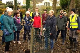 A group of people stand around an oak tree at Tregoniggie Woodland