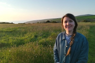 Image of a person smiling in fields with the background