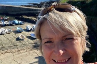 Image of a person smiling with boats in the background