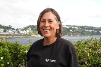 Image of a person smiling with a background of sea and coastline