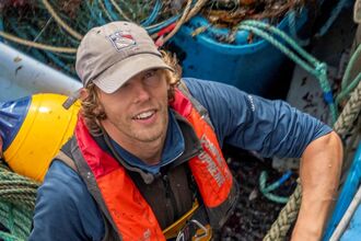Image of a person in a fishing boat with nets and ropes
