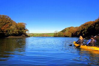 Blue skies over a river with a yellow kayak on the right of the image