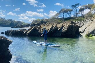 A person paddles on a stand up paddleboard under blue skies 