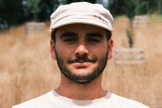 Image of a person wearing a hat with leaves in the foreground