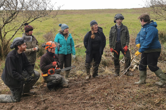 A group of volunteers stand together being trained in new skills as part of volunteering with cornwall wildlife trust 