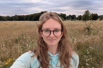 Image of a person smiling with a background of trees and fields