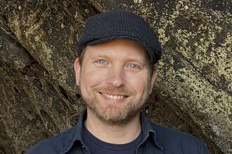 A person smiling and standing in front of rocks 