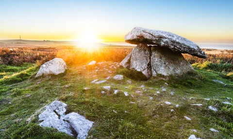 the stone quoits of chun are shown with a beautiful setting sun in the background, capturing the raw beauty of Penwith