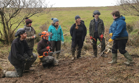 A group of volunteers stand together being trained in new skills as part of volunteering with cornwall wildlife trust 