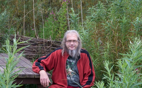 Mark sat on a bench surrounded by trees 