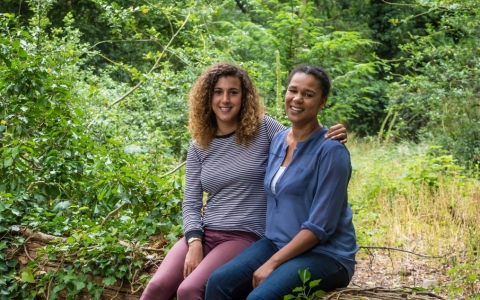 Juliet and Amy sit together on a fallen tree