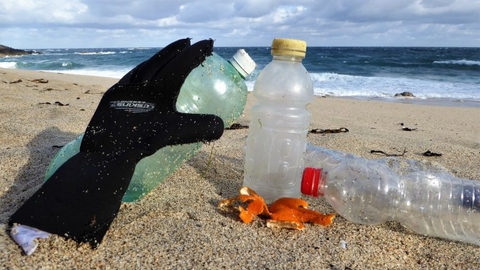 Wetsuit glove and plastic bottles on a Cornish beach