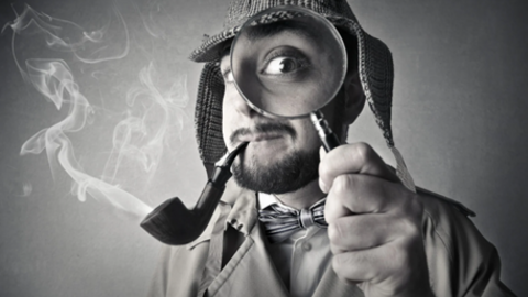 Black and white image of a detective, holding up a magnifying glass over one eye