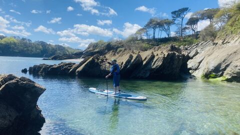 A person paddles on a stand up paddleboard under blue skies 