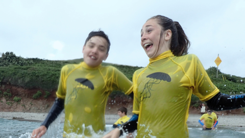 Two smiling young people jumping in the sea