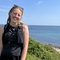 A girl stands on a hill, with the vast ocean