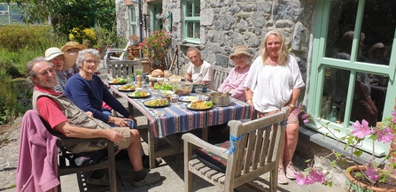 Volunteers sat around an outdoor garden table, posing and smiling at the camera