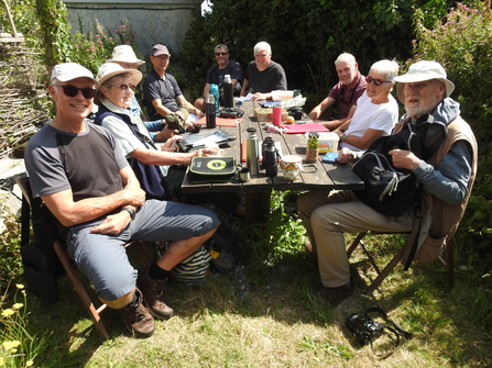 People gathered round a table enjoying tea and cake 