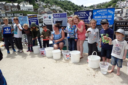 Image shows children and their parents stood in a line holding the crabs they have caught at a crabbing competition.