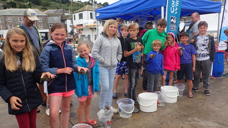 Image shows a group of children and their parents holding the crabs they've caught at a crabbing competition in Cornwall 