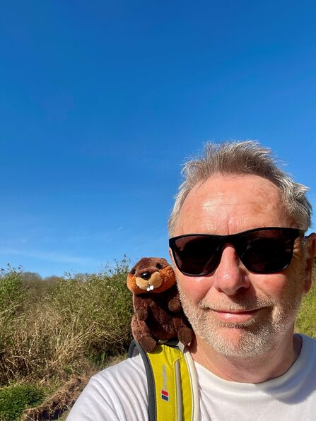 Paul Foord and his mascot Justin Beaver, pictured smiling towards the camera under blue skies