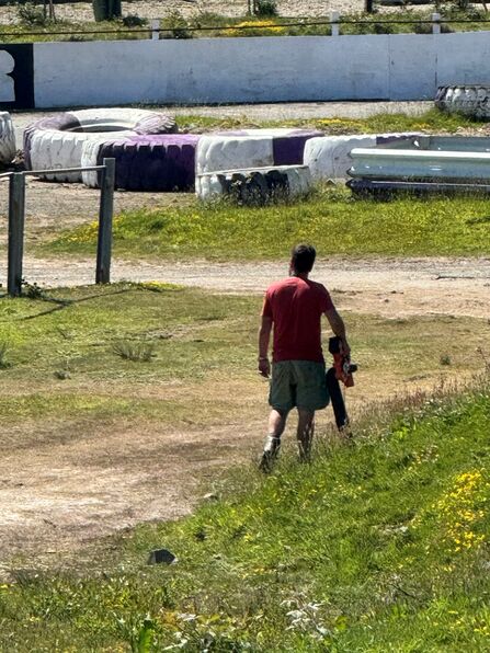 Person walking across a raceway site carrying equipment.