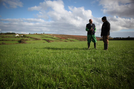 A farmer and farm advice cornwall wildlife trust team member stand and survey the land
