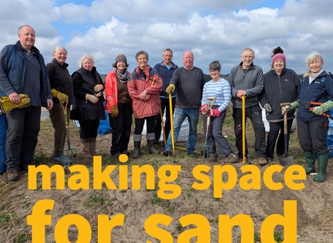 Image of volunteers posed with spades with the Making Space for Sand logo
